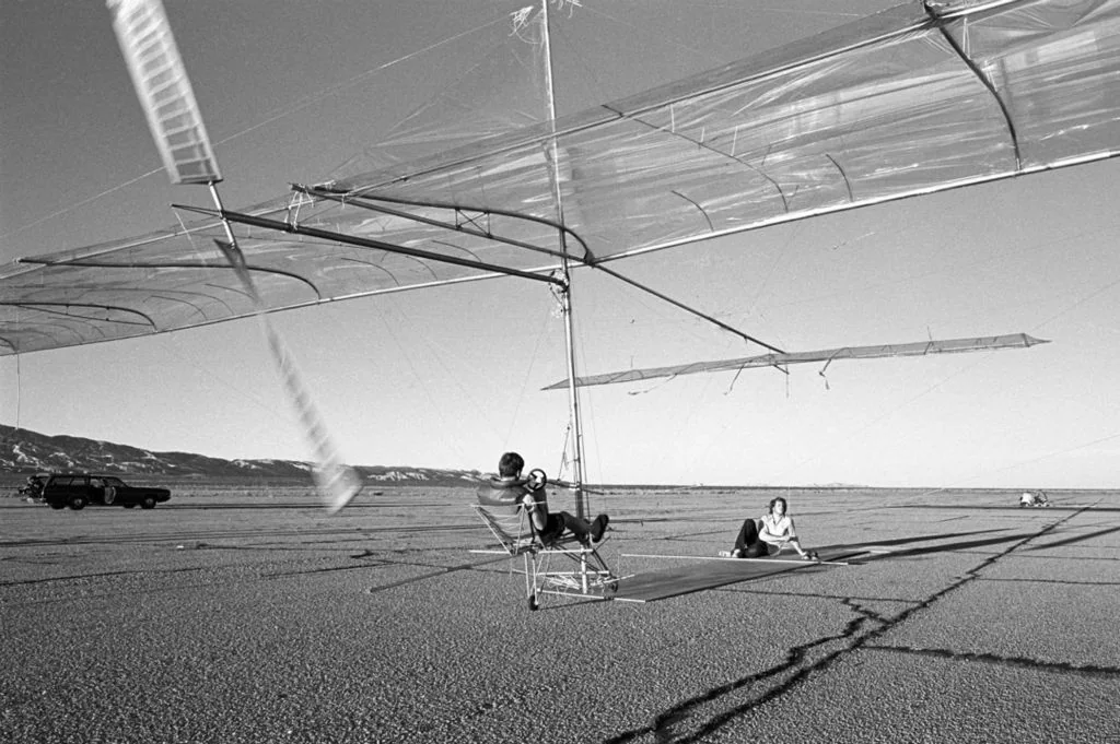 Greg Miller pedals an early Gossamer Condor with an uncovered fuselage at Mojave Airport, January 14, 1977.