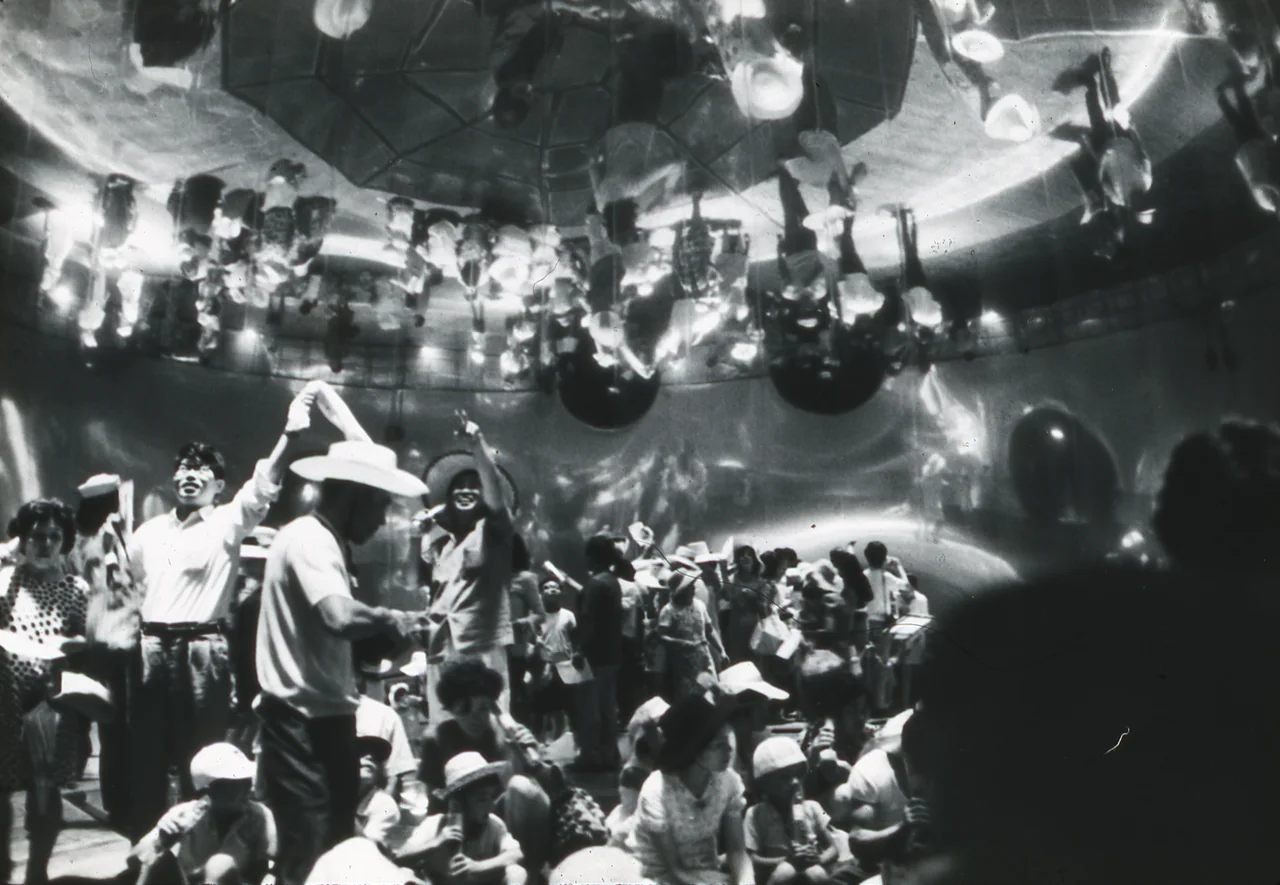 Visitors in the Pepsi Pavilion’s mirror dome see inverted images of people suspended above them.